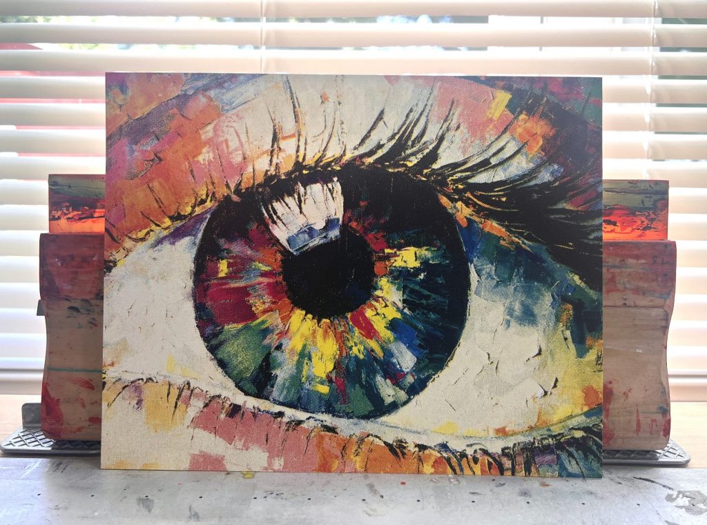 CMYK Eye Painting screen print standing upright, featuring a realistic eye created with cyan, magenta, yellow, and black halftone layers.