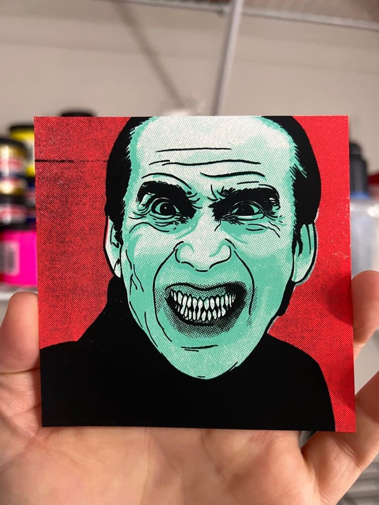 Hand holding Nicolas Cage Renfield mini horror screen print to show artwork size and scale.